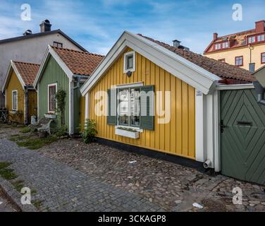 Historic one story wooden houses with colorful yellow, green siding in Kalmar Sweden old town built originally for local sailors Stock Photo