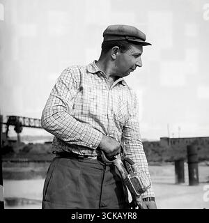 A Soviet concrete worker at the construction site of the Sloviansk GRES in Mykolaivka, Ukrainian SSR, in 1970. The archival photograph captures a man using a concrete vibrator to compact the concrete mix during the pouring of a foundation. This production portrait is a tribute to the hard physical labor of the builders, whose hands created the giants of Soviet energy, and it conveys the atmosphere of a "great construction project of communism." Stock Photo