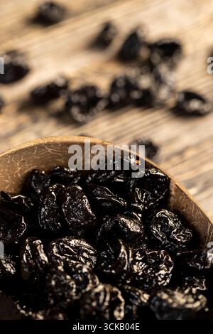 black prunes made from ripe plums in a coconut shell plate, dried plums in a bowl made from natural materials Stock Photo