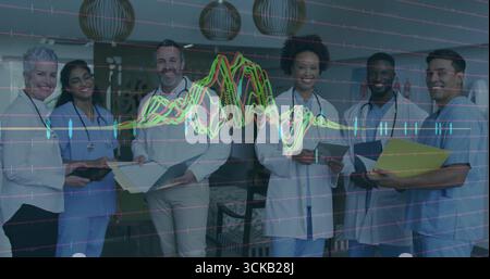 Standing team wearing scrubs labcoats in lounge holding stethoscopes with waveform data overlay Stock Photo