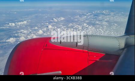 Red aircraft engine and wing seen from high altitude above the clouds Stock Photo