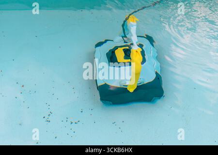 A robotic pool cleaner in action in the water to clean the dirty bottom of a swimming pool Stock Photo