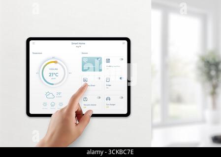 Finger touching smart home tablet app to adjust appliances and monitor temperature Stock Photo