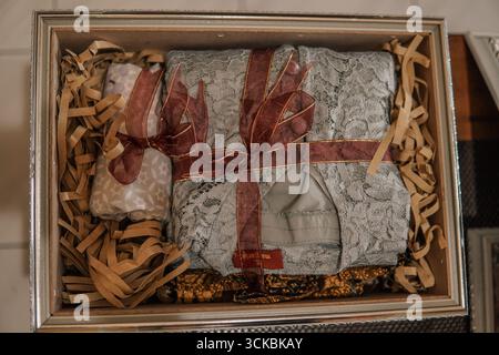 A beautifully wrapped gift box containing lace clothing and decorative items, surrounded by shredded paper filler Stock Photo