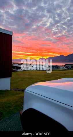 A dramatic sunset illuminates the sky with scattered clouds over ...