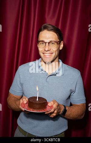 Portrait of Young Adult Man Smiling While Presenting Chocolate Cake Stock Photo