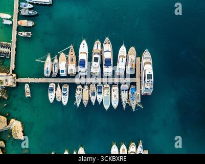 Aerial view of an array of yachts moored at a pier, reflecting in the turquoise waters of the harbor, Marsaxlokk, Malta. Stock Photo