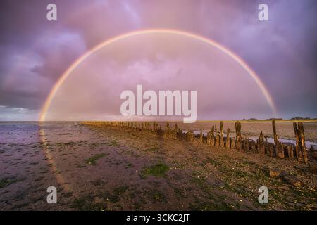 A rainbow over the Waddensea at sunset in Holland Stock Photo