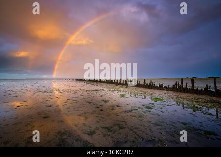 A rainbow over the Waddensea at sunset in Holland Stock Photo