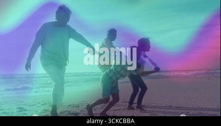 Senior couple in summer clothes walking while holding kids' hands on sandy shore, with ocean water. Family bonding, leisure, outdoor, serenity, harmon Stock Photo