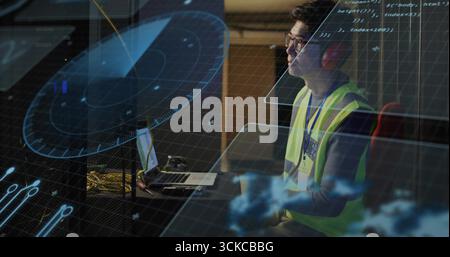 Mature Korean engineer wearing vest monitoring radar overlays on laptop in control hub, copy space. Innovation, technology, cybersecurity, data, surve Stock Photo