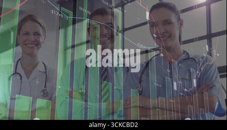 Crossing arms, medical team wearing stethoscopes and scrubs displaying financial charts in corridor. Healthcare, collaboration, analytics, professiona Stock Photo