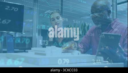 Examining architectural model, two colleagues using tablet and laptop in office, with data overlay. Collaboration, mentorship, innovation, professiona Stock Photo