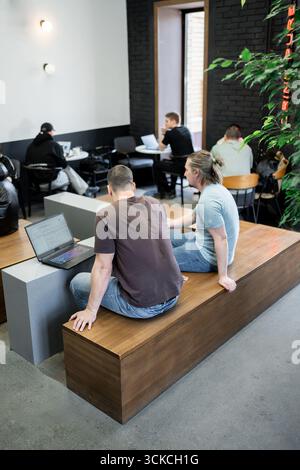 Programmers discussing over laptop working at startup. Office, business and friends together in teamwork with notebook, laptop and coffee workplace Stock Photo