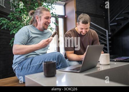 Two laughing It Software engineers working on project and programming in coffee shop. Successful start up project concept. Stock Photo