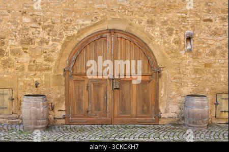 Old brown round double wooden door in a stone facade Stock Photo