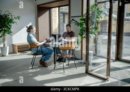 Programmers discussing over laptop working at startup. Office, business and friends together in teamwork with notebook, laptop and coffee workplace Stock Photo