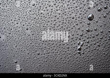 Side view of black surface with dense water droplets forming textured condensation background. Stock Photo