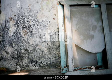 old glass window frame broken leaning on dirty wall Stock Photo