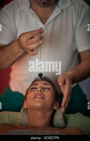 alternative medicine therapist making a treatment on Caucasian female with plumb line Stock Photo