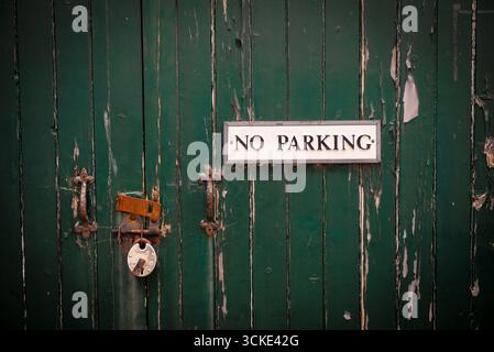 Weathered Green Door with Padlocks and No Parking Sign Stock Photo