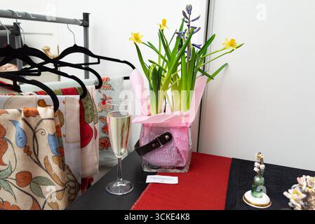 Colorful flowers in pink wrap with champagne on table in boutique setting. Stock Photo