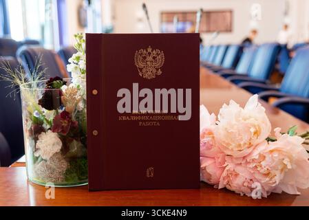 Graduation thesis book with flowers on conference table in office setting. Stock Photo