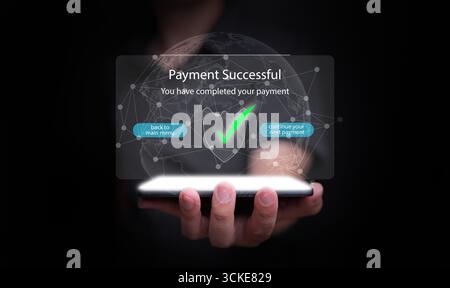 Hand holding smartphone with holographic screen showing successful payment. Symbol of secure fintech, international online business, digital transacti Stock Photo