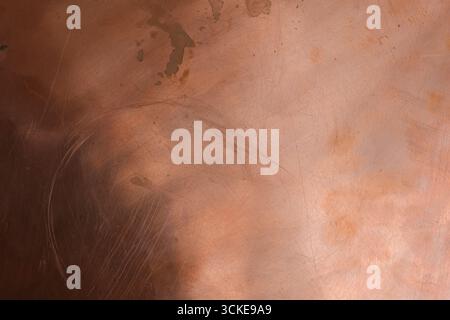 The scratched and stained copper surface is dark in the lower left corner. Copper oxidation. Space for design. Stock Photo