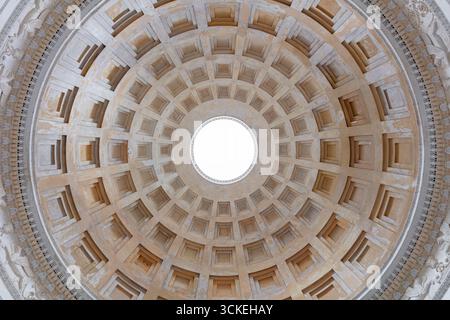 Symmetrical architectural dome with concentric coffers radiating toward a bright oculus, forming a graphic circular pattern. Clean, neutral background Stock Photo