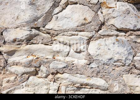 Close view of a rubble‑stone wall with cement mortar and varied rock shapes, offering a realistic, rustic masonry texture. Ideal for architectural ref Stock Photo