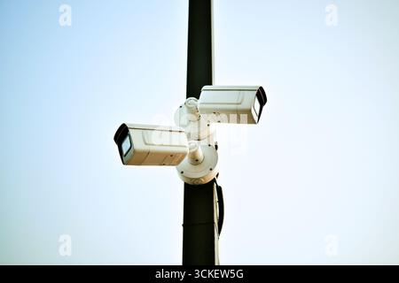 CCTV Cameras is installed on pillar to monitor traffic conditions on a city street. Two white surveillance cameras outdoors. Stock Photo