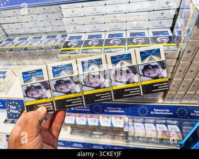 Varna, Bulgaria - Aug 31, 2025: Hand holding multiple Parliament cigarette  packs with graphic health warning labels inside Varna Airport duty free sho  Stock Photo