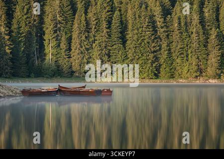 Wooden boats on calm Black Lake with forest reflections in Durmitor National Park, Montenegro, peaceful summer morning view Stock Photo