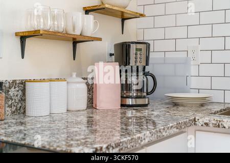 Coffee maker in bright white kitchen corner with ceramic jars, plates cups Stock Photo