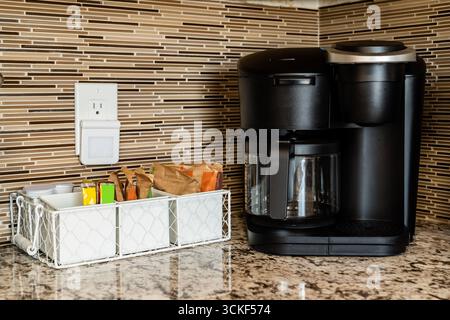 Black coffee maker pot single serve pod with caddy, tile backsplash, and granite countertop Stock Photo