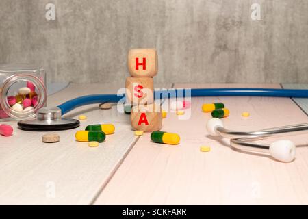 wooden cubes displaying HSA on a medical document with a stethoscope, symbolizing Health Savings Account, healthcare savings, and financial planning f Stock Photo