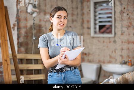 Woman making notes on indoor construction site Stock Photo
