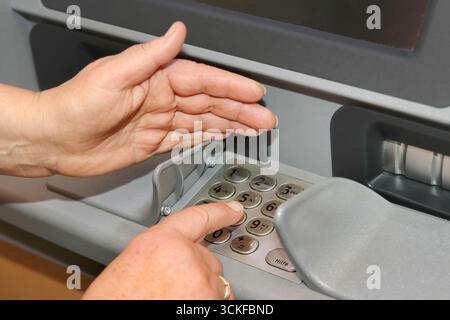 Woman enters PIN at ATM Stock Photo