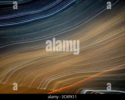 ''Dynamic abstract light trails created with long-exposure photography at night, featuring flowing lines against a dark background.'' Stock Photo