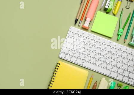 Composition with computer keyboard and different school supplies on green background, closeup Stock Photo