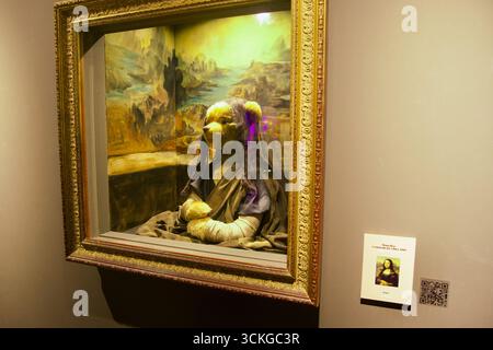 A teddy bear dressed in dark robes and veil poses inside a gilded frame styled after Leonardo da Vinci’s Mona Lisa, with a painted landscape backdrop Stock Photo