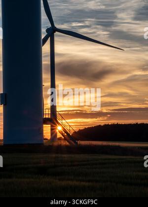 Wind turbine at sunset with sun rays shining through ladder platform Stock Photo