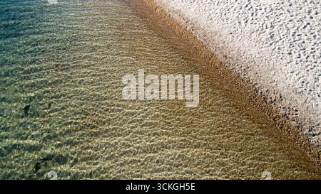 The water is calm and clear, with a sandy beach in the background Stock Photo