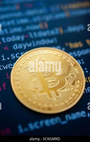 Golden bitcoin coin over computer code symbolizing cryptocurrency technology and blockchain system Stock Photo
