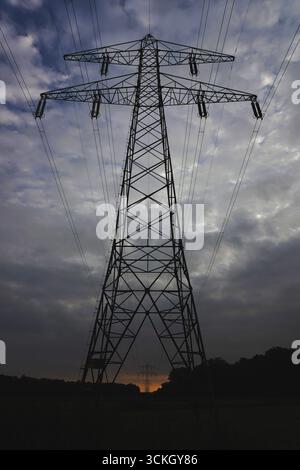 High-voltage transmission tower against a dramatic cloudy sky Stock Photo