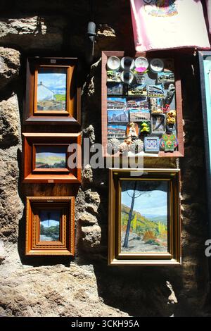 A collection of framed art and souvenirs hangs on a rustic stone wall Stock Photo