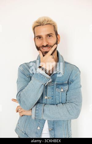Young man poses confidently with a smile and stylish denim jacket Stock Photo