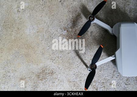 Small gray quadcopter on a gray background. Quadrocopter close-up. Stock Photo