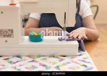 Woman using sewing machine with purple fabric Stock Photo
